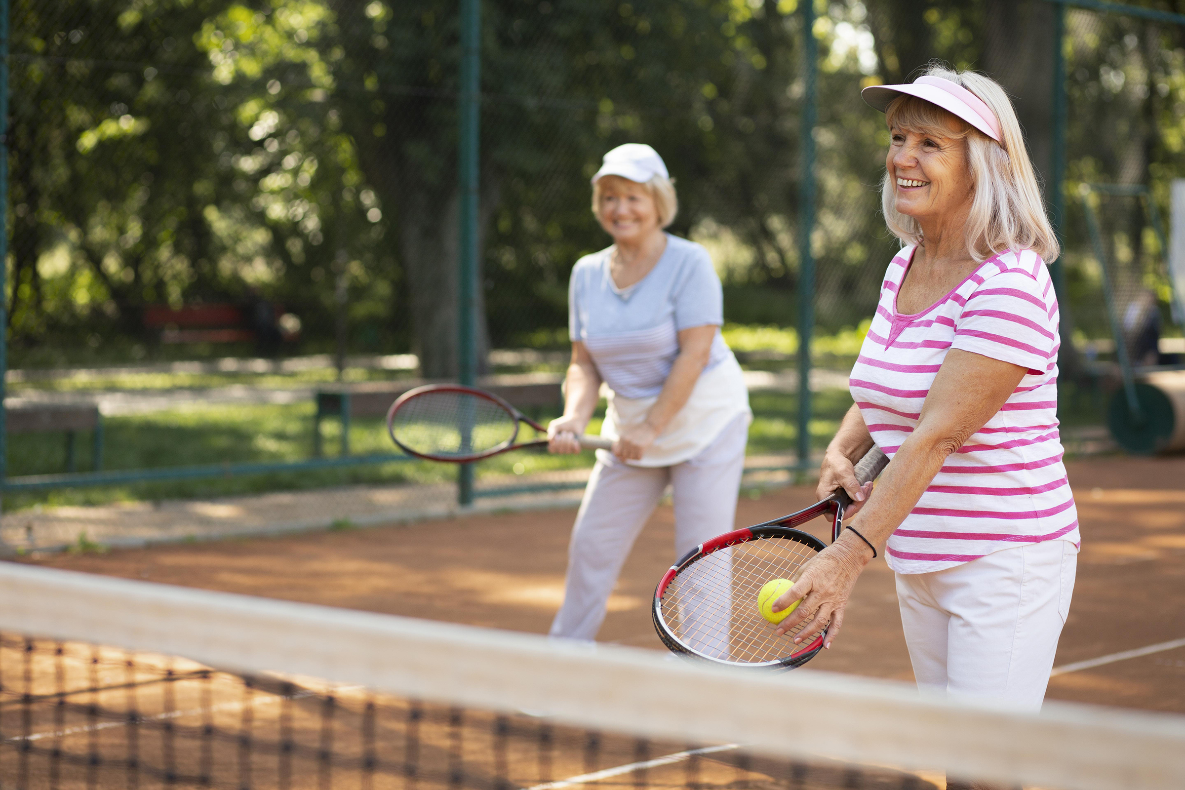 two senior friends playing tennis